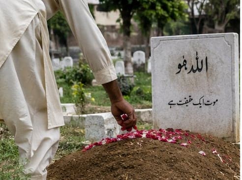 Rose petals being scattered by hand over an earthen grave