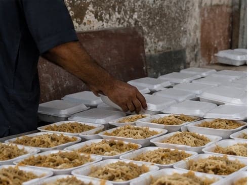 Portions of biryani being packed into boxes on a table